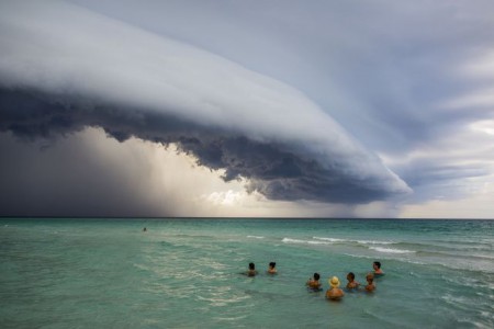 "SEA CHANGE" Las personas en el mar parecen hipnotizadas ante una nube enorme que pasa en una playa en Varadero Cuba. El intimidante fenómeno puede atribuirse a tormentas eléctricas.  Cortesía: National Geographic Fotógrafo: Giovani Cordioli https://yoursh